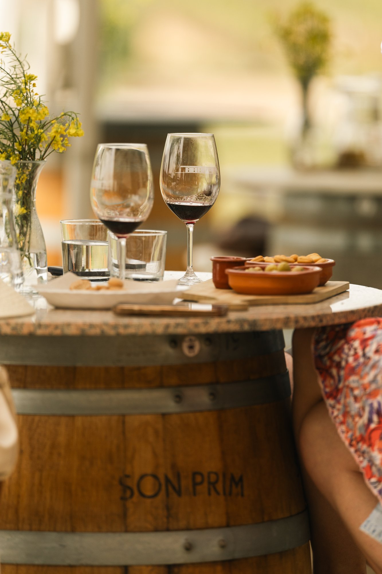 A table among the vines at Son Prim: two glasses, flowers and a barrel